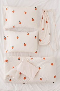 an unmade bed with white sheets and oranges printed on the pillow cases, along with two pillows