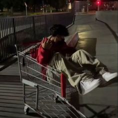 a person sitting in a shopping cart with their head on his hand and reading a book