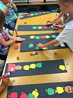 several children are sitting at a table playing with magnets on the paper and glue