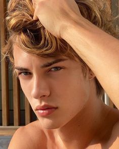 a shirtless young man is holding his hair