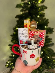 a hand holding a coffee mug filled with holiday gifts