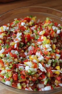 a glass bowl filled with chopped vegetables on top of a wooden table