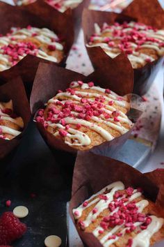 some cupcakes with white frosting and red sprinkles on them