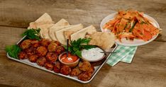 a tray filled with food next to a bowl of carrots and pita bread