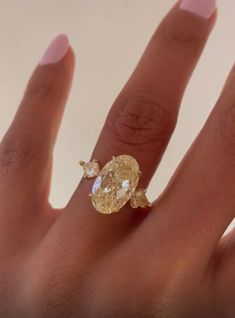 a woman's hand with a yellow diamond ring on it