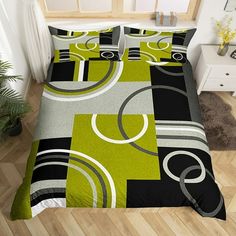 a bed covered in a green and black comforter next to a white nightstand with a potted plant