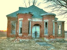 an old red brick house sitting in the middle of a field with no leaves on it