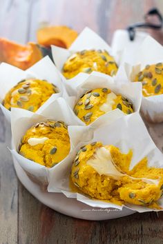 several muffins with pumpkin and seeds in paper wrappers on a white plate