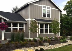 a house with landscaping in front of it and flowers growing on the side of the house