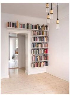 a book shelf filled with lots of books on top of a hard wood floor next to a doorway