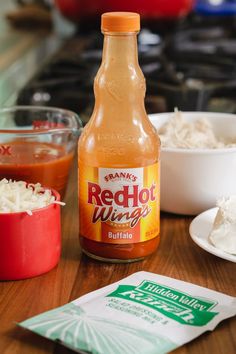 a bottle of hot sauce sitting on top of a wooden table next to other food