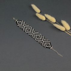 two pieces of beaded bracelets with feathers on them sitting next to each other