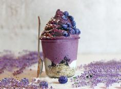 a dessert in a glass with blueberries and other toppings on it next to lavender flowers