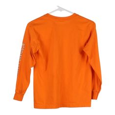 an orange long sleeved shirt hanging on a white hanger with the words,