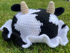 a crocheted cow laying in the grass with horns on it's head