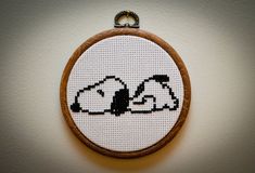 a cross - stitch hoop hanging on the wall with two dogs in it's eyes