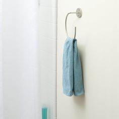 a blue towel hanging on the wall next to a white shower curtain in a bathroom