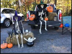 two skeletons sitting on hay bales in the back of a truck with pumpkins