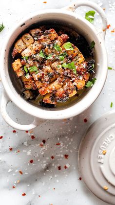 a white bowl filled with tofu and garnished with parsley on top