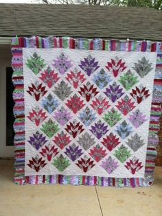 a colorful quilt hanging from the side of a brick building in front of a house