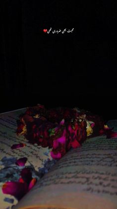 an open book sitting on top of a bed in the dark with flowers all over it