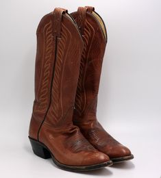 "vintage Tony Lama brown leather western boots. .Women's size 5.5B brown leather western boots with black piping at the side seam. pointy toes. decorative stitching on the instep and uppers in a light color. cowboy heels. 13.75\" tall from the floor widest part of the ball measures 3.5\" measured on the outside sole 10.25\" toe to heel measured on the outside with heel against the wall leather has some scuffs and bends. there are some darker areas on the top of the shoe that I have shown in the Vintage Pointed Toe Boots For Rodeo, Fitted Vintage Brown Western Boots, Vintage Western Boots With Pointed Toe, Fitted Vintage Brown Snip Toe Boots, Vintage Pointed Toe Boots For Western Events, Vintage Pointed Toe Boots For Western-themed Events, Southwestern Brown Snip Toe Boots, Brown Southwestern Snip Toe Boots, Vintage Brown Snip Toe Boots