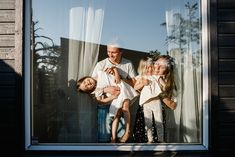 an older man and two young children standing in front of a window