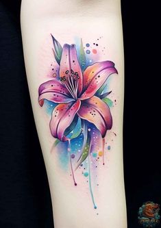 a colorful flower tattoo on the leg with watercolor paint splashs and sprinkles