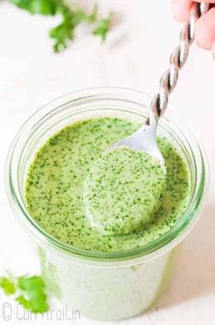 a green smoothie in a glass with a silver straw sticking out of the top