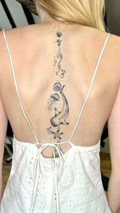 the back of a woman's white dress with fish tattoos on her lower back