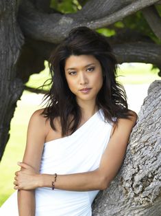 a beautiful young woman leaning against a tree