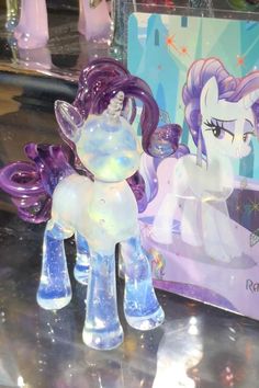 a glass figurine of a pony next to a box with an image on it