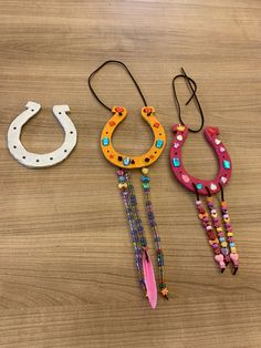 three different necklaces on a wooden surface with beads and chains hanging from them,