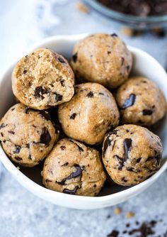 a white bowl filled with chocolate chip cookie doughnuts on top of a table