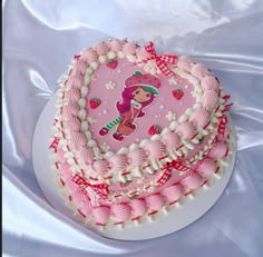 a pink cake with white frosting and strawberry design on top, sitting on a plate