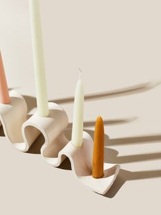 three candles sitting on top of each other in front of a white wall and floor