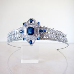 Be bold in blue!  This regal, handmade showstopper is silver plated and encrusted with cubic zirconia crystals.  Attach to the head by stringing provided elastic ribbon through loops at the back. Heigh at centre: 5cm  Width: 15cm Elegant Crystal Headpieces For Weddings, Elegant Headpieces With Teardrop Crown For Gift, Regal Tall Crown Headpieces For Wedding, Elegant Teardrop Crown Headpiece For Gifts, Elegant Headpiece With Teardrop Crown For Gift, Regal Wedding Headpiece With Structured Crown, Regal Structured Crown Wedding Headpiece, Regal Structured Crown Headpiece For Wedding, Elegant Silver Crown For Wedding