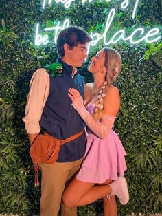 a man and woman standing next to each other in front of a sign that says the best place