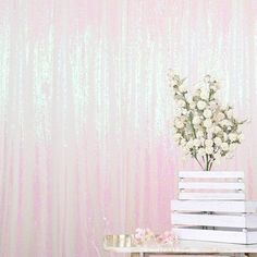 a vase with flowers sitting on top of a stack of books in front of a pink wall