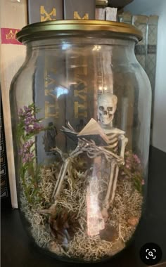 a glass jar filled with fake skeletons and plants