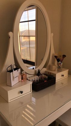 a white vanity with a round mirror on it's side and some drawers underneath