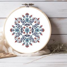 a cross stitch pattern is shown on a white background with a wooden frame and some dried flowers