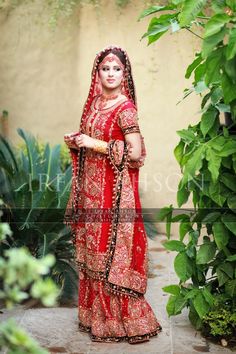 a woman in a red and gold bridal gown is posing for the camera with her hands on her hips