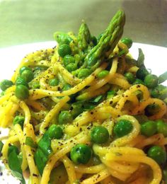 a white plate topped with pasta and asparagus on top of it's side