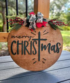 a merry christmas sign hanging on the back of a wooden porch chair with ribbon and bow