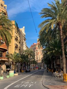 a street with palm trees and buildings on both sides, in the middle of town