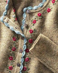 a sweater with flowers on it is shown in close up, and has buttons at the bottom