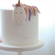 a white cake with pink and purple icing on it's face, decorated like a unicorn