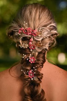 the back of a woman's head with braids and flowers in her hair