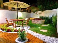 an outdoor patio area with wooden decking and green grass, surrounded by small plants